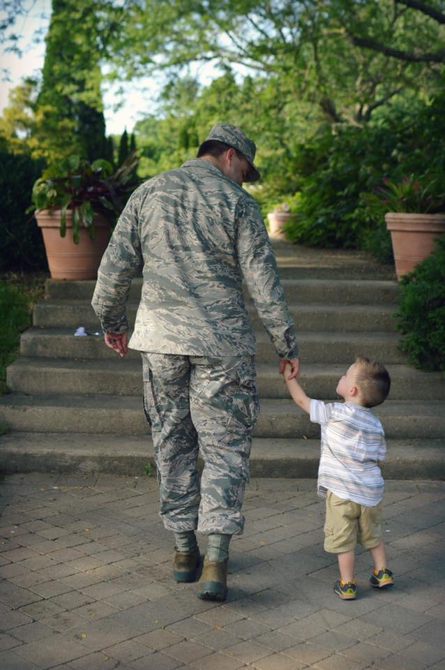 military service member father walking and holding hands with young son